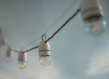 Low angle view of light bulb hanging against sky