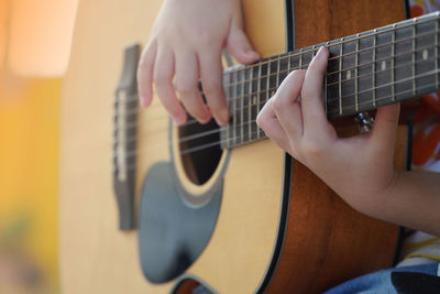 Midsection of man playing guitar
