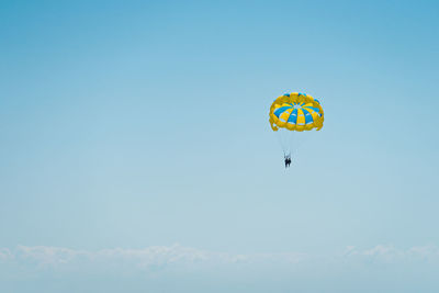 Low angle view of person paragliding against sky