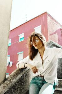 Young woman looking away while sitting outdoors