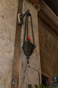 Low angle view of electric lamp hanging on wall in building