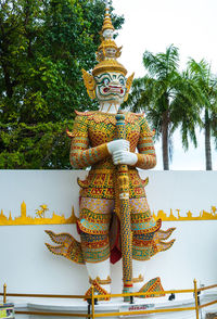 Low angle view of statue against trees and building