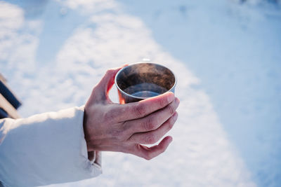 Close-up of hand holding water in cup during winter