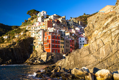 Italian village riomaggiore against cliff and sea during sunset, cinque terre, la spezia, italy