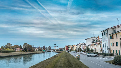 Empty road by buildings against sky