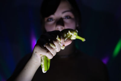 Portrait of woman squeezing banana in darkroom