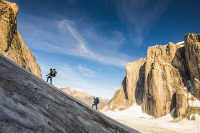 Backpackers hiking up glacier, ascending mount asgard, baffin island.