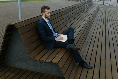 Young man using mobile phone while sitting on bench
