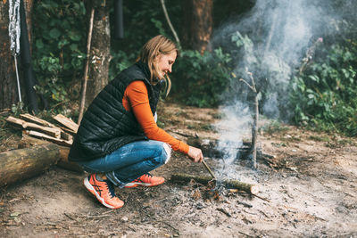 A young woman lights a fire during a hike in the forest