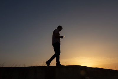 Side view of silhouette man standing against clear sky during sunset