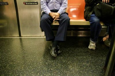 Low section of man sitting in train