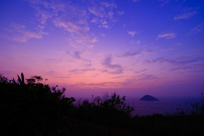 Silhouette trees on landscape against romantic sky at sunset