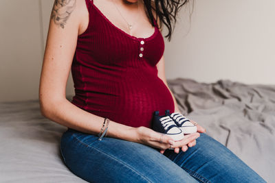 Midsection of woman holding shoes while sitting at home