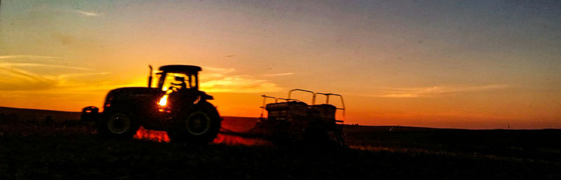 Tractor on field against sky during sunset