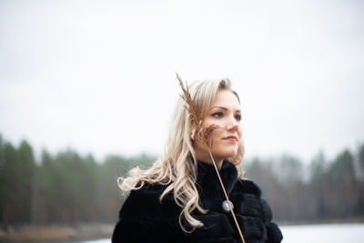 Portrait of beautiful woman against sky during winter