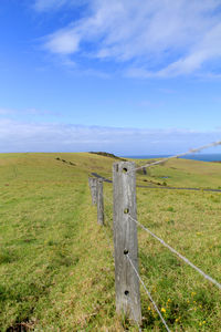 Wooden fence on field against sky