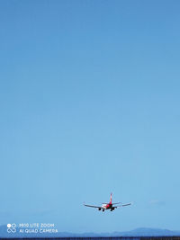 Low angle view of airplane flying against clear blue sky