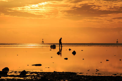 Silhouette people on beach against sky during sunset