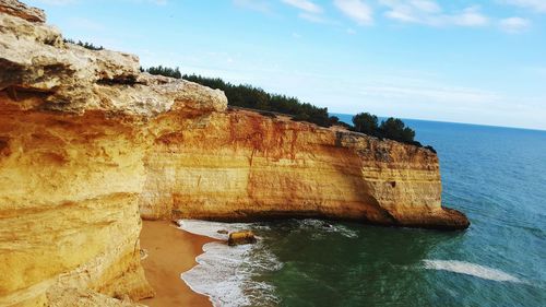 Rock formations by sea against sky