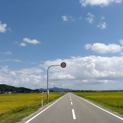 Empty road amidst green landscape against sky