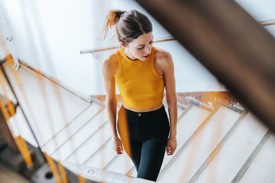 Young woman standing on steps seen through railing