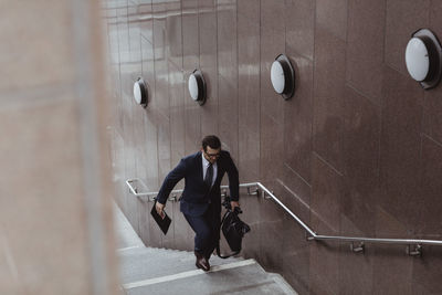 Businessman with bag climbing staircase in city