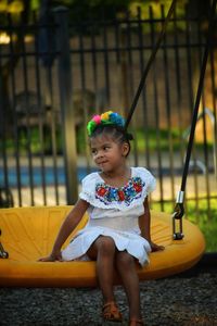 Portrait of girl sitting on swing at playground in mexican attire