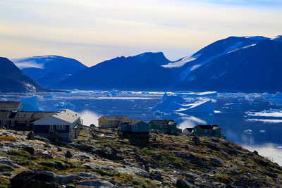 Houses on cliff by icebergs in sea