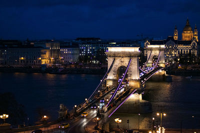 Illuminated bridge over river in city at night