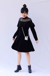 Full length portrait of woman standing against wall
