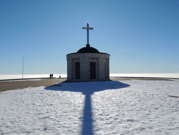 Church by building against clear blue sky during winter