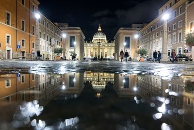 Reflection of building in puddle at night