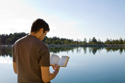 Man standing by lake against sky