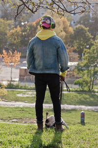 Rear view of man with dog standing on tree