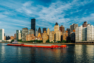 Modern buildings by river against sky in city