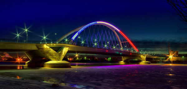 Illuminated bridge over river against sky at dusk