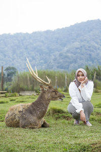 Beautiful asian girl playing with the javan rusa or rusa timorensis at ranca upas, ciwidey, ndonesia