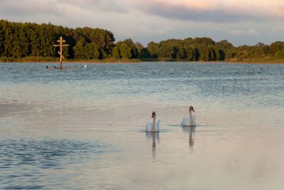 People in lake against sky