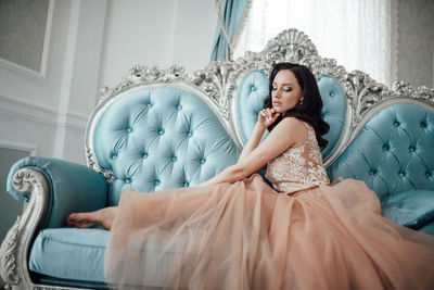 Young woman sitting on sofa at home