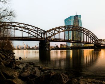 Arch bridge over river against clear sky in city during sunset