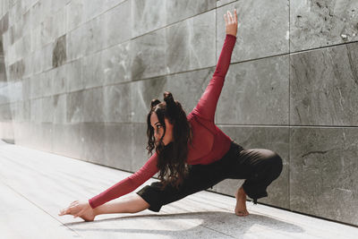 Full length of woman dancing on floor against wall