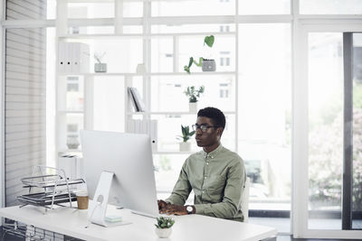 Young man using phone while sitting on table