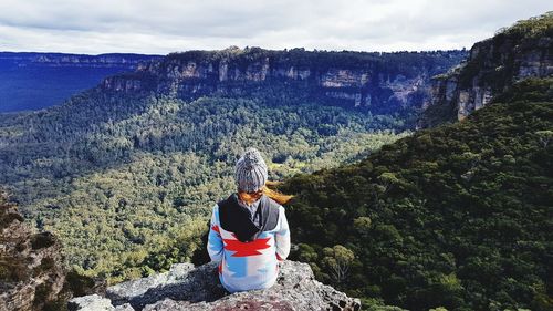 Rear view of woman standing on rocky mountains