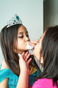 Portrait of mother fixing daughter makeup who is wearing costume.