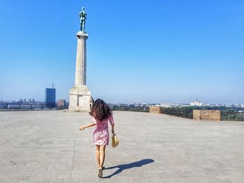 Woman with arms outstretched against sky in city