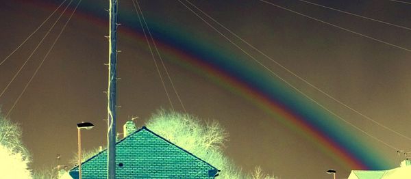 Low angle view of rainbow over illuminated building against sky