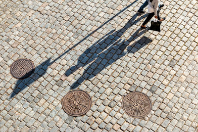 Low section of people walking on cobblestone street