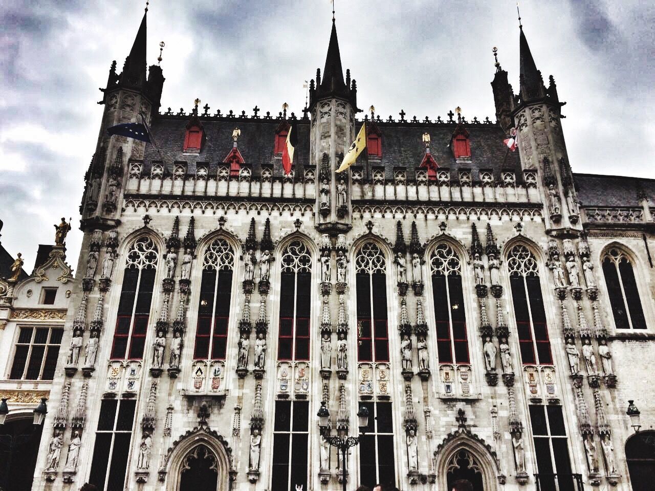 architecture, building exterior, low angle view, built structure, travel destinations, sky, cloud - sky, place of worship, facade, history, spirituality, outdoors, religion, tourism, gothic style, no people, day, travel, statue, window, sculpture