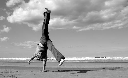 Full length of woman doing wheel on beach