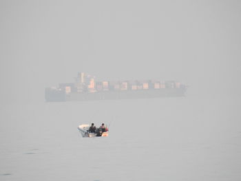 People on boat in sea against sky